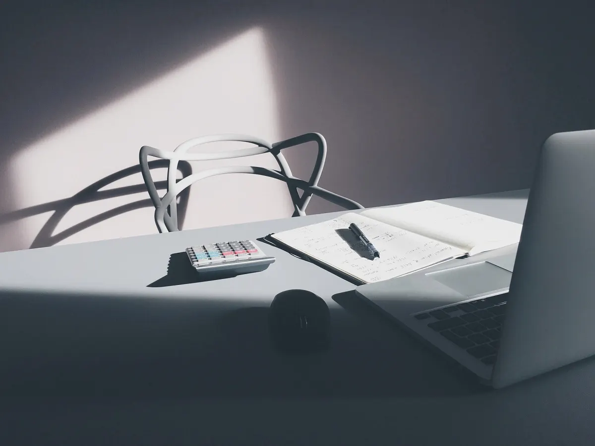 Bureau avec une calculatrice, un cahier et un ordinateur portable pour vérifier le calcul d'un salaire net